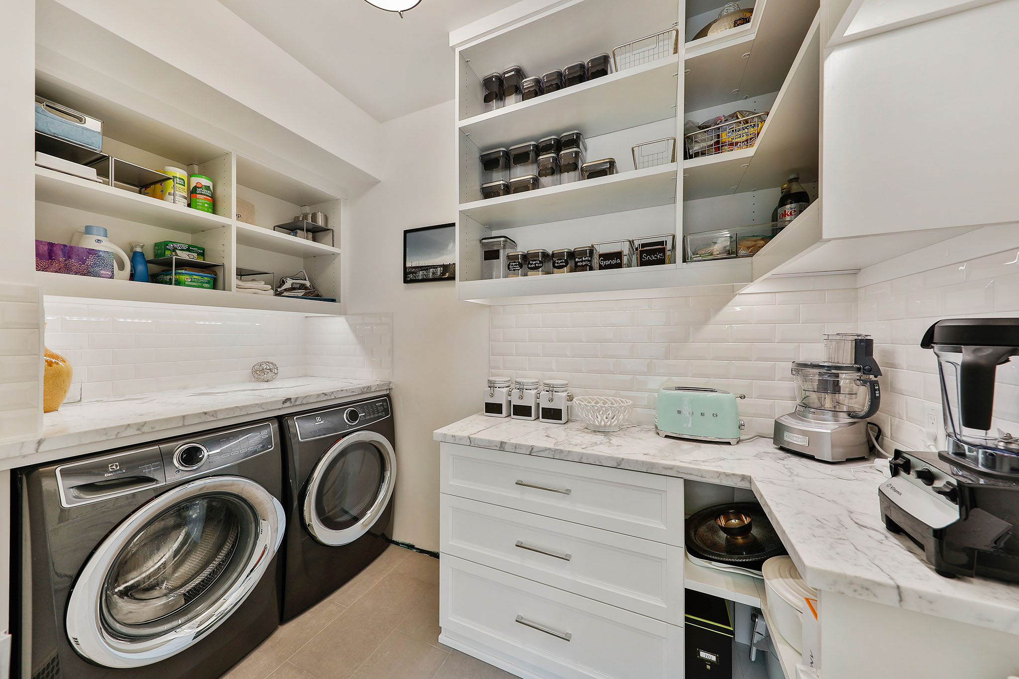 Full sized washer and dryer  housed in the walk-in pantry, outfitted with marble counters
