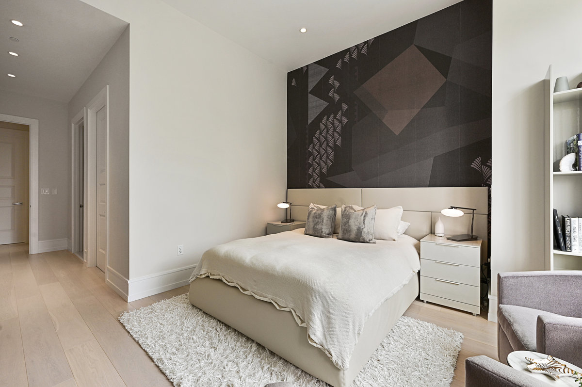 The bedroom features an accent wall behind the bed’s headboard, display shelves, seating area and generous walk-in closet.