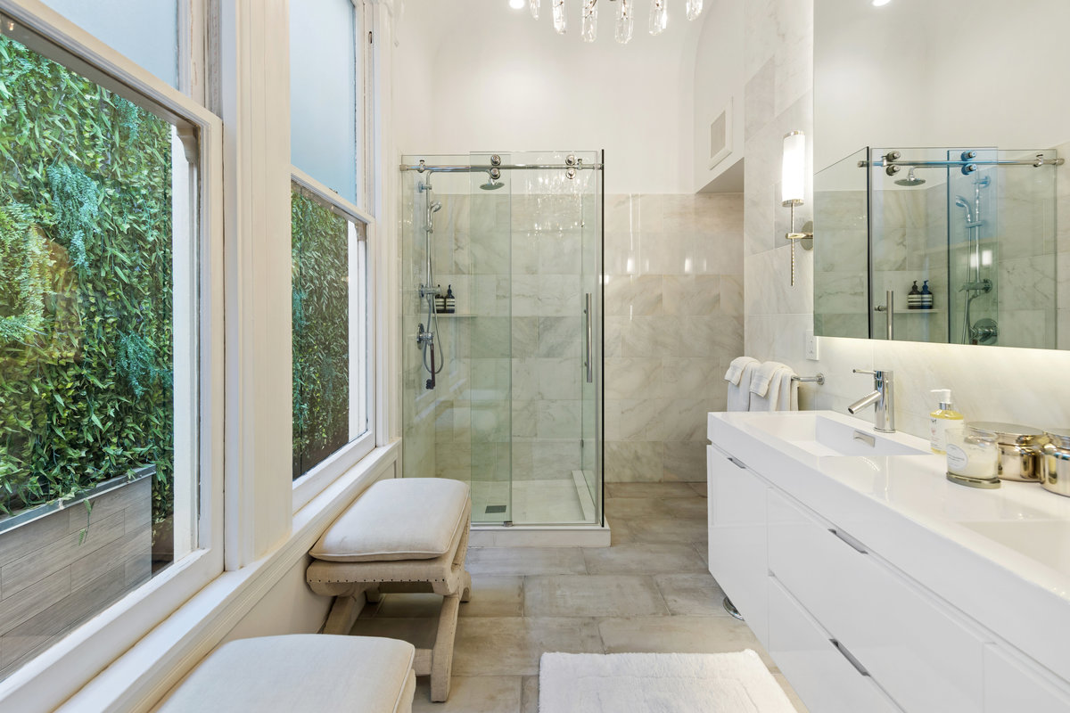 Primary bath features modern white and stone bath with shower, dual sinks and windows providing natural light