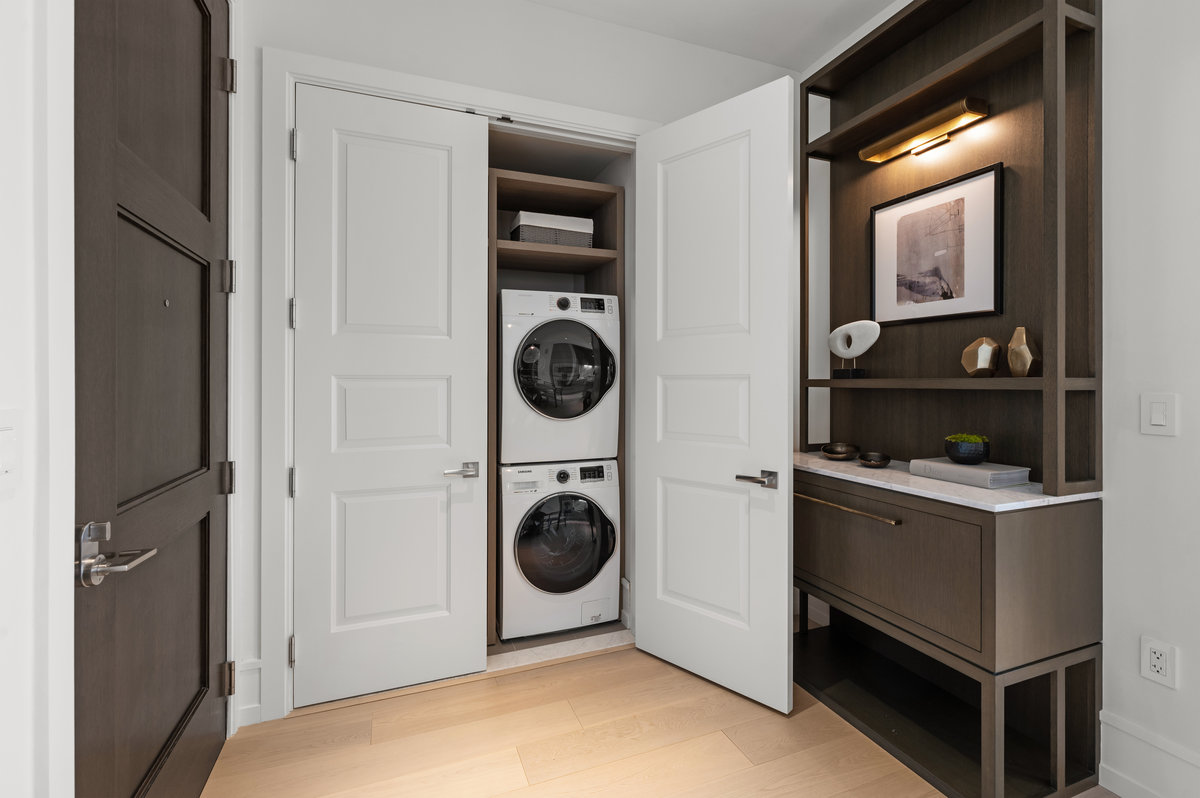Washer dryer (on right) plus coat closet/pantry shelving (on left) are located near entry of the residence.