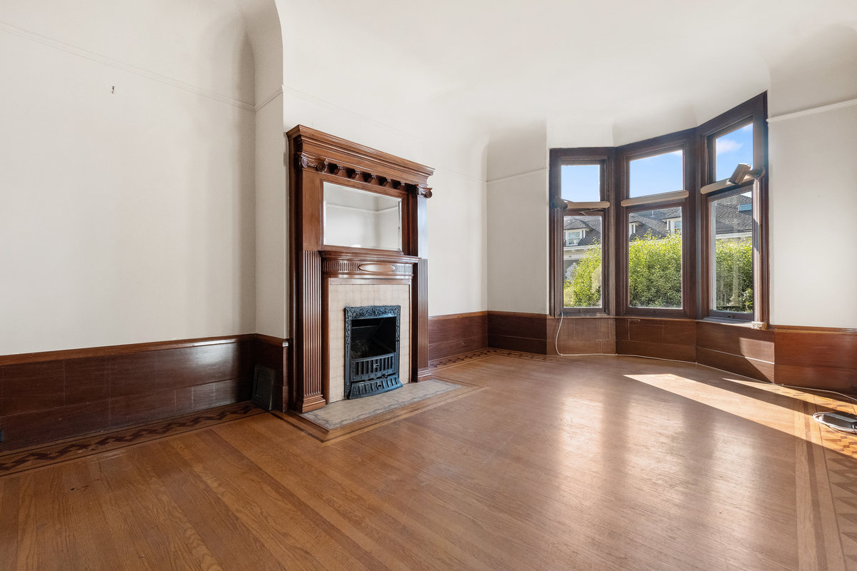 Southern portion of living room with west-facing windows and vintage fireplace