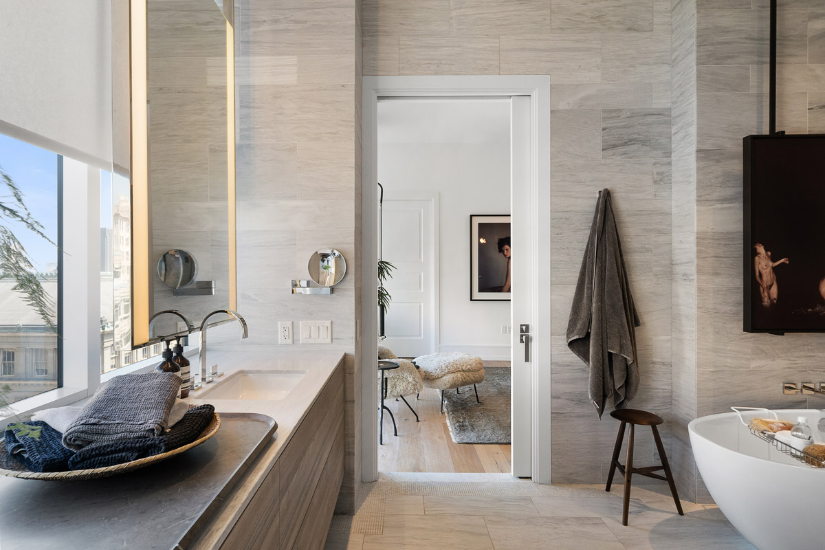 Marble clad primary bath with full-width window, heated floor