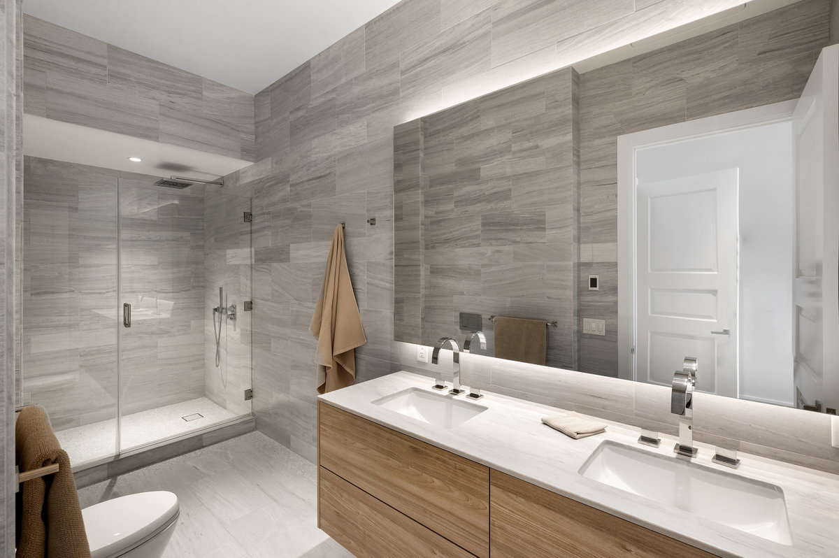 Full bath clad in grey marble,  with dual sinks, heated floor, large shower