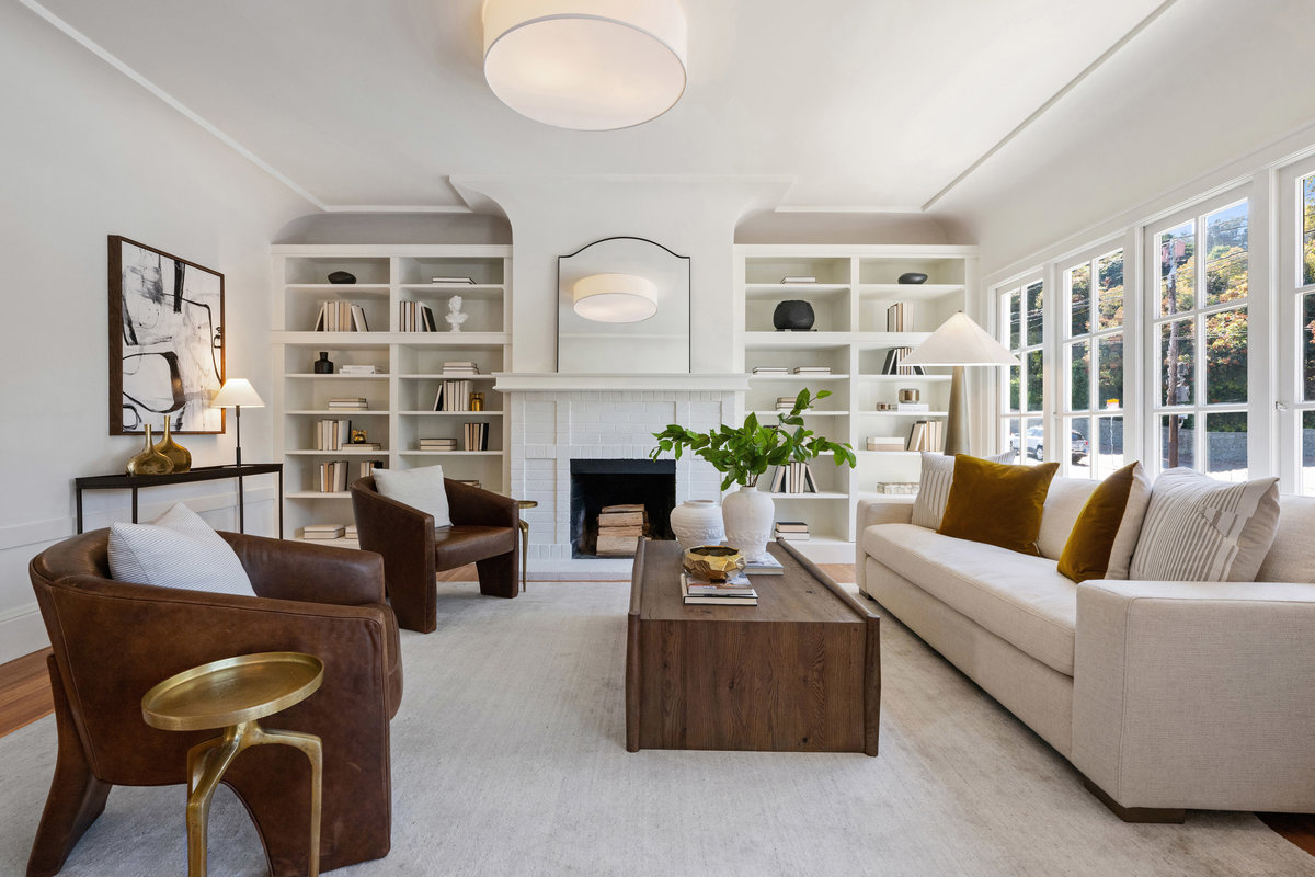 Living room with fireplace, display shelves, wall of west windows opening to decorative balcony