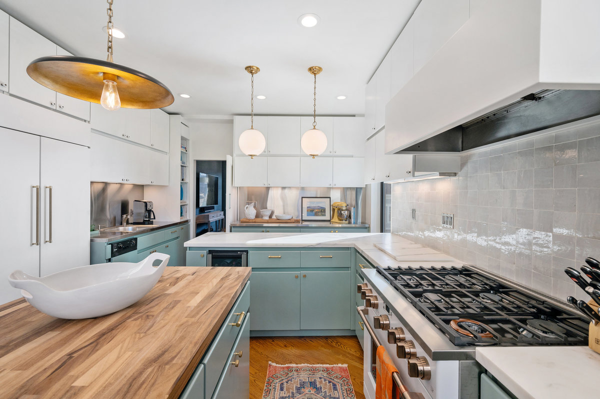 Chef's gas kitchen with ample marble, wood and stainless steel counters; seating below the globe pendants