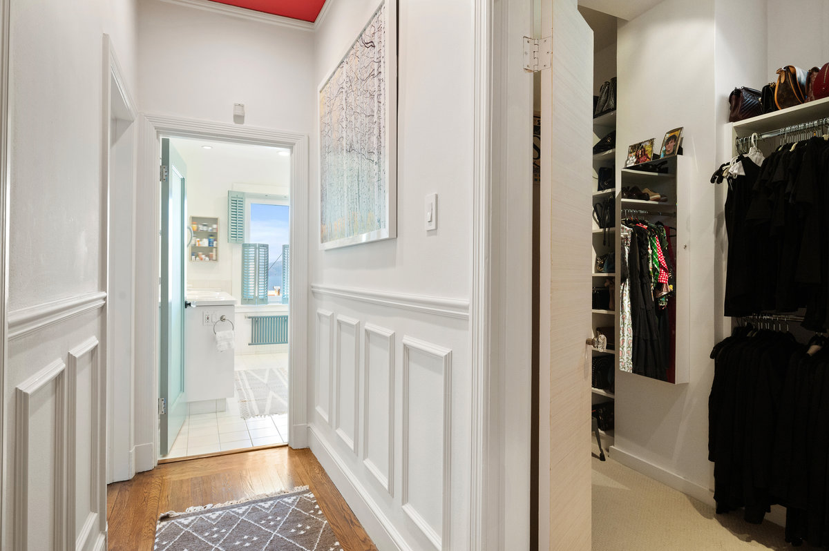 Hall within primary suite leads to two walk-in closets