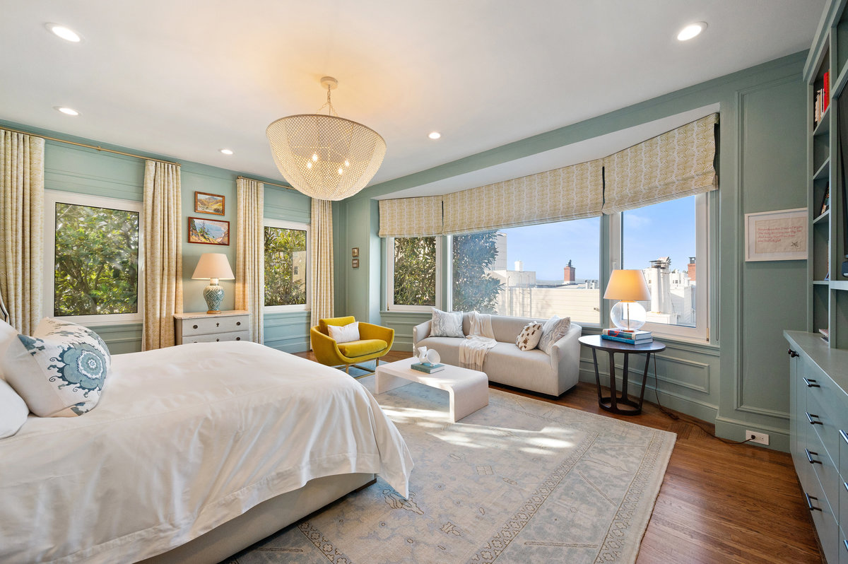 Located at the north end of the residence, the generous primary suite with north windows providing glimpses of the Bay from the bed and seating area