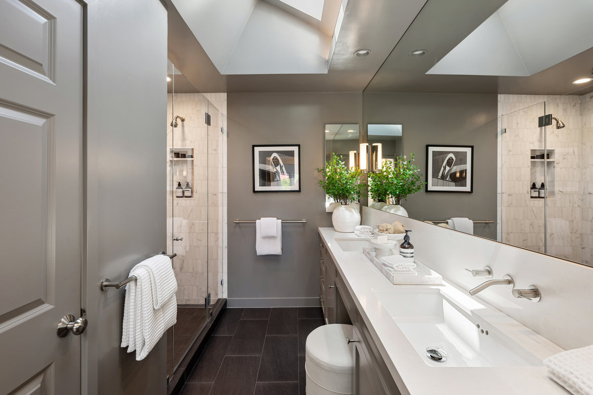 Primary bath with dual sinks, vanity seating, shower, water closet, skylight
