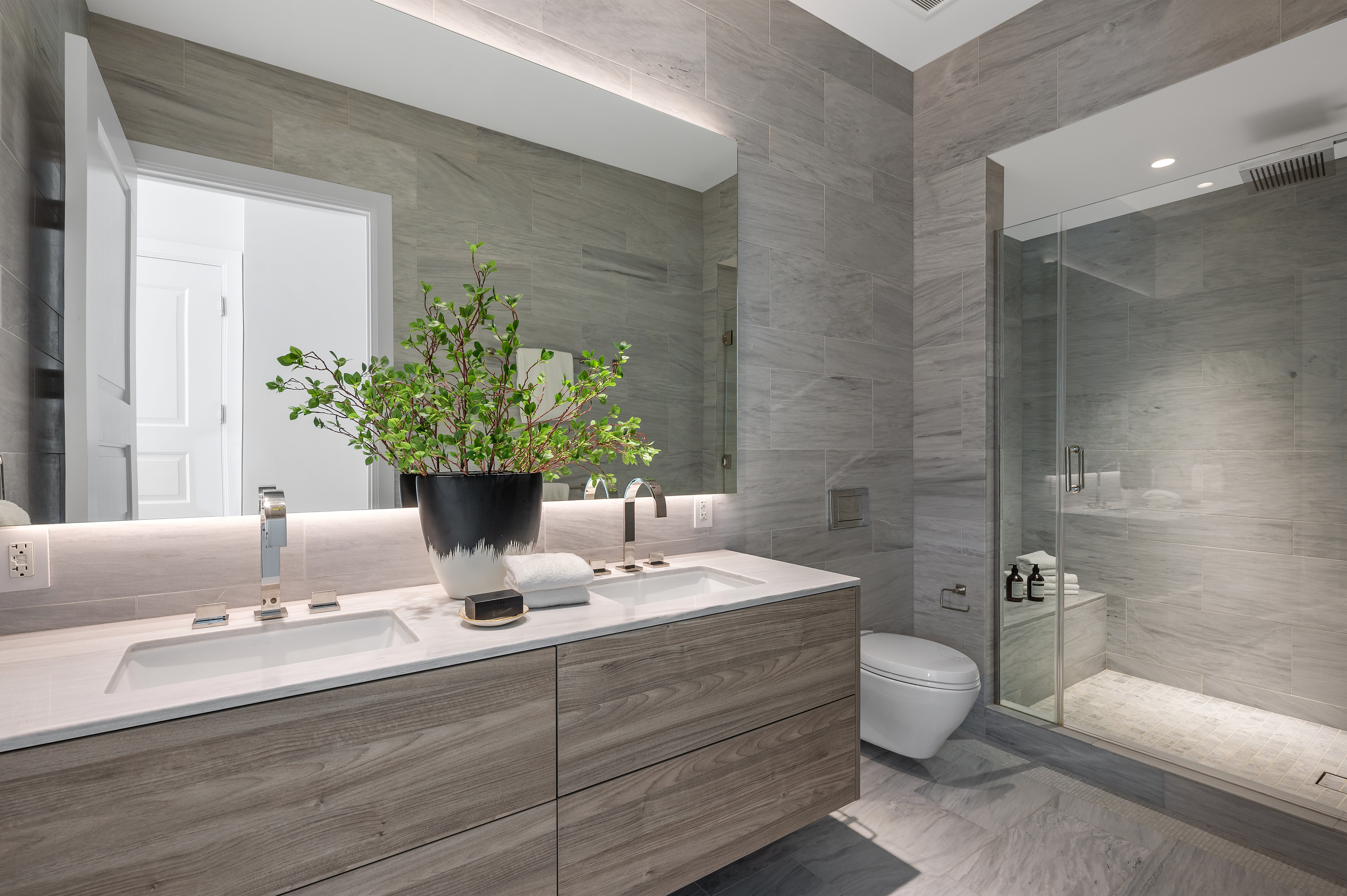 Primary bath, clad entirely in stone, dual sinks, radiant floor heat, large shower with seat